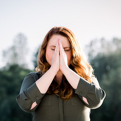 A woman with her palms together, eyes closed, practicing mindfulness to help with her ADHD symptoms and avoid ADHD Tax