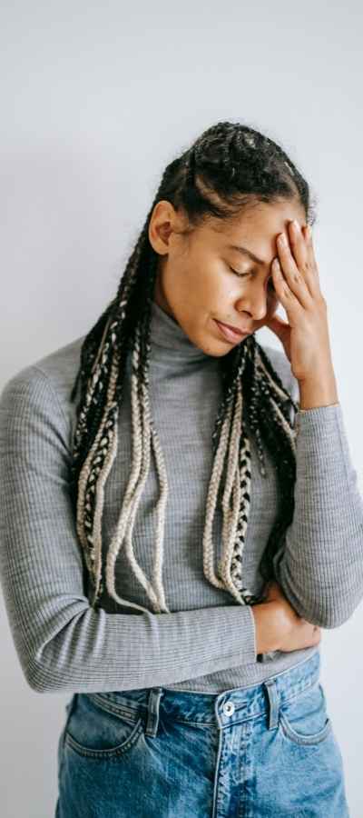 A Black woman stands holding her head exhausted with mental fatigue A Black woman stands holding her head exhausted with mental fatigue