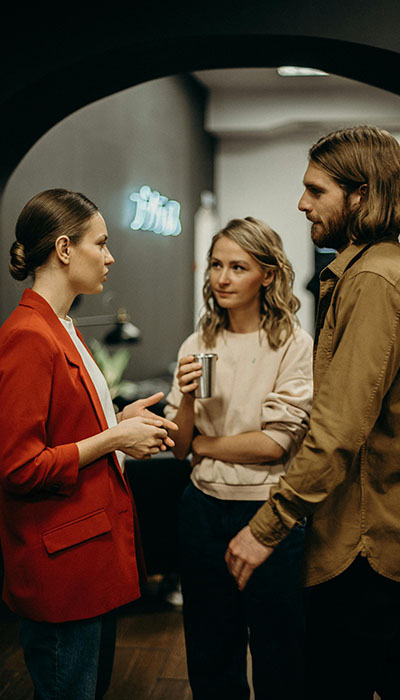 A group of three people talking together, one isn't smiling because they are struggling with communication as an adult with executive functioning challenges A group of three people talking together, one isn't smiling because they are struggling with communication as an adult with executive functioning challenges