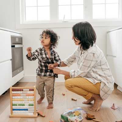 A parent and child in a kitchen with toys part of everyday life