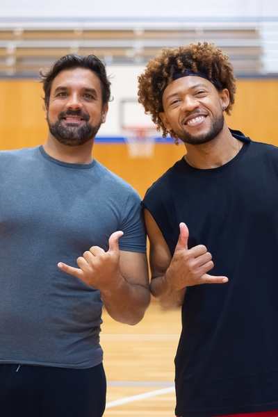 Two men standing together, accountability buddies to exercise by playing basketball Two men standing together, accountability buddies to exercise by playing basketball