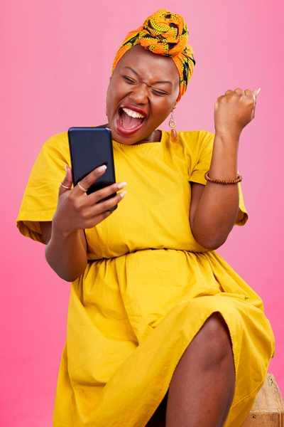 A Black woman celebrates in a yellow dress while looking at her cell phone, having completed a nagging task A Black woman celebrates in a yellow dress while looking at her cell phone, having completed a nagging task