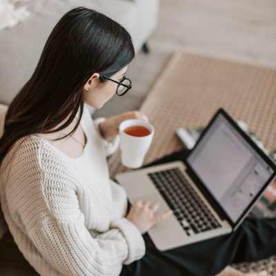 A woman with glasses sits with a mug in one hand using her laptop for high productivity from managing her executive functioning skills A woman with glasses sits with a mug in one hand using her laptop for high productivity from managing her executive functioning skills