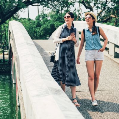 Two relaxed, happy women crossing a bridge in the sunshine Two relaxed, happy women crossing a bridge in the sunshine