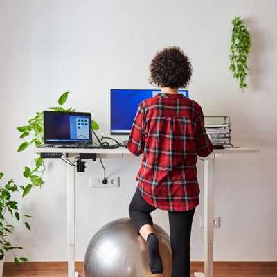 Woman working at a standing desk to support executive function by allowing her to seek movement Woman working at a standing desk to support executive function by allowing her to seek movement