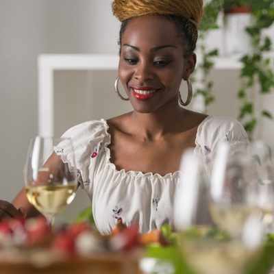 A Black woman looks down at her table full of food for dinner after successfully using her meal plan A Black woman looks down at her table full of food for dinner after successfully using her meal plan