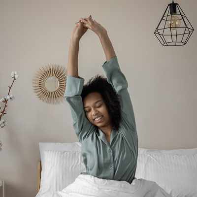 A Black woman stretching in bed after a good night of sleep A Black woman stretching in bed after a good night of sleep