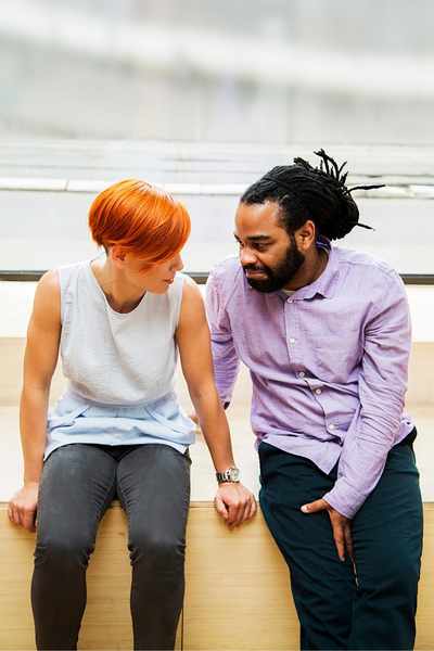 A redheaded woman and a Black man are sitting together talking through a communication problem by using their mental flexibility to remain grounded A redheaded woman and a Black man are sitting together talking through a communication problem by using their mental flexibility to remain grounded