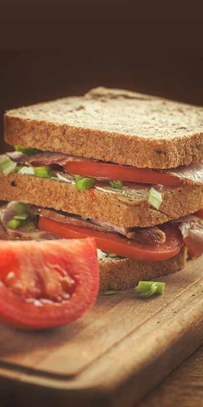 A sandwhich on a cutting board beside a tomato, made as an easy solution when ADHD fights following a meal plan A sandwhich on a cutting board beside a tomato, made as an easy solution when ADHD fights following a meal plan