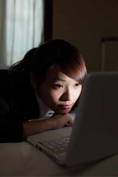 A woman using her computer in the dark struggling to transition away from an activity due to her ADHD inhibition struggles A woman using her computer in the dark struggling to transition away from an activity due to her ADHD inhibition struggles
