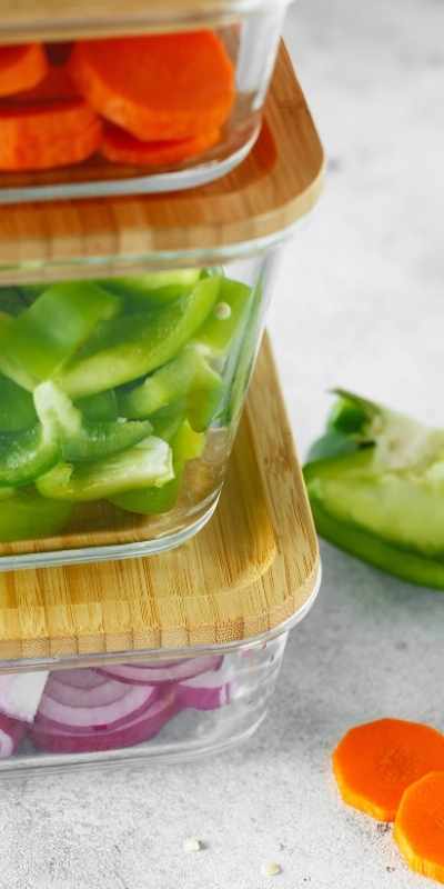 Vegetables pre-cut for meal prep and stored in stacked glass and bamboo containers Vegetables pre-cut for meal prep and stored in stacked glass and bamboo containers