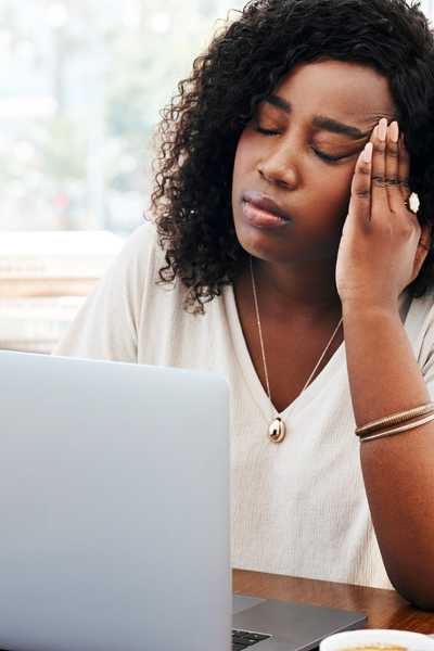 A Black woman visibly stressed from invisible labor and emotional labor