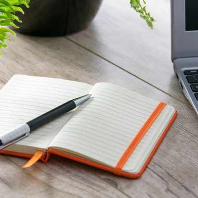 A notebook and pen beside a laptop to make a cheatsheet for neurodivergent brains at work