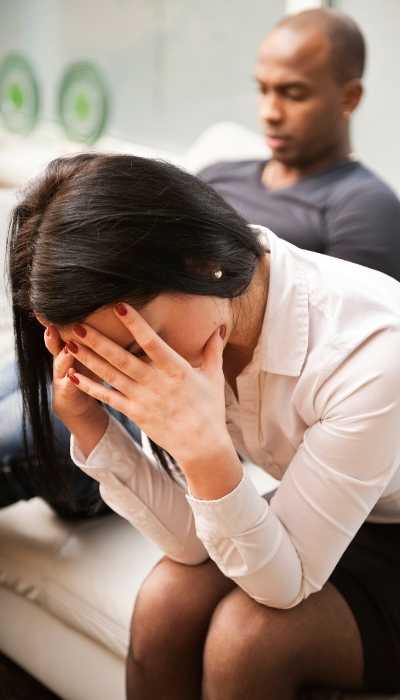 An overwhelmed woman needing to hold boundaries in her relationship with the man sitting behind her