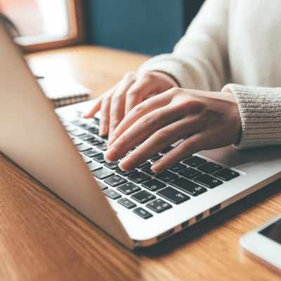 Woman's hands typing on an open laptop