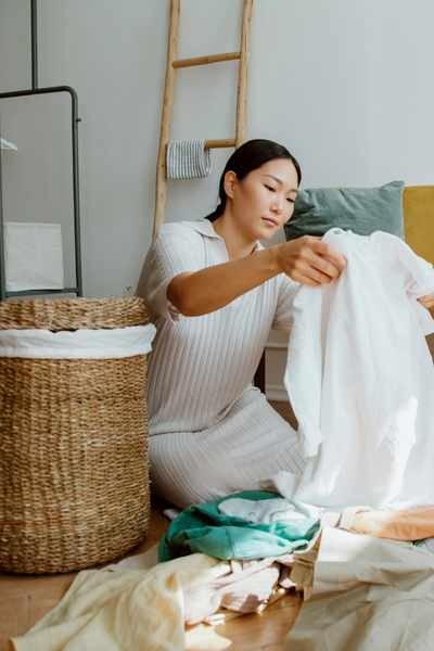 A woman sits on the floor folding laundry at the end of the day being flexible with when and where the task gets done