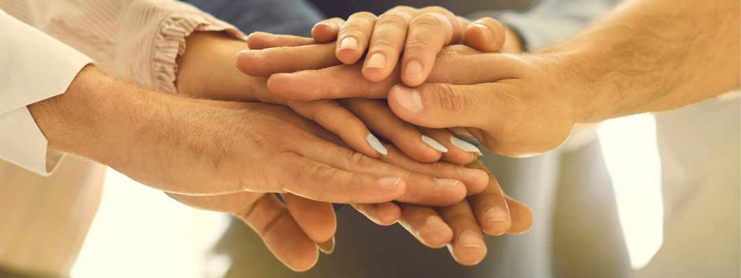 ADHD professional community of practitioners showing support and camaraderie with stacked hands in a circle ADHD professional community of practitioners showing support and camaraderie with stacked hands in a circle