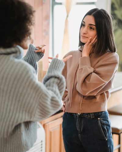 Two women are having an argument and the one facing the camera is staring in annoyance at the other woman