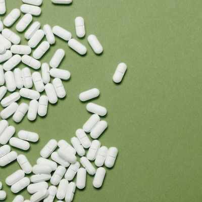 White pills on a green background used for an abundance of medication that wasn't taken and the tests to improve memory for that task
