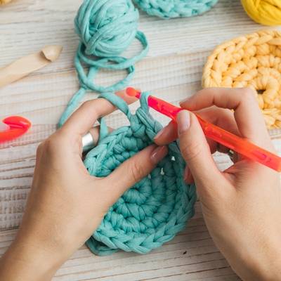 A closeup of a woman's hands as she practices her crochet hobby