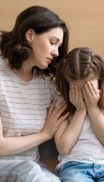A woman calms an upset child by getting close and showing regulation cues for the child to mirror for co-regulation