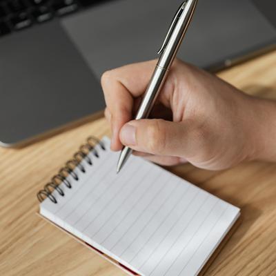 Holding a pen over a note pad to make a to-do list and break tasks into more manageable sub-tasks for neurodivergent adults