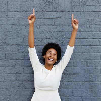 A woman with her arms up celebrating her wins with tiny habits