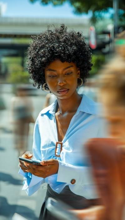 A woman on her phone staring into the distance struggling with overwhelm