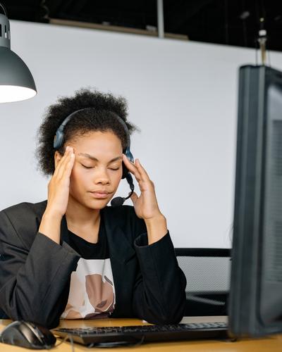A person overwhelmed with hands on temples and eyes closed