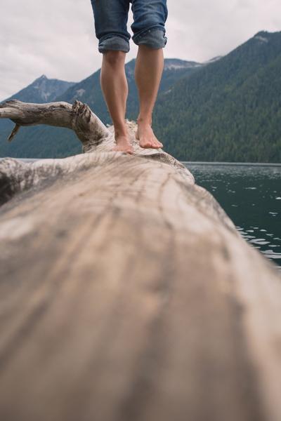 walking on a log over water in the mountains to illustrate breathing room and relaxation