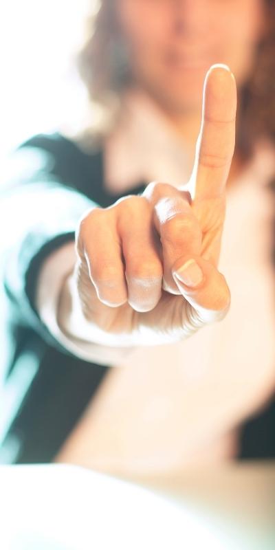 A woman holding her index finger up in the wait sign to pause between stimulus and response when practicing patience